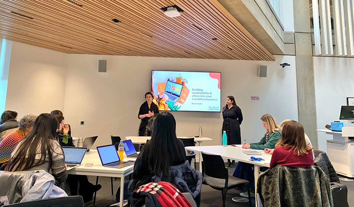 Caroline Summers and Rachel Baker standing in front of a group of students. Caroline is introducing Rachel and Rachel is looking at Caroline.