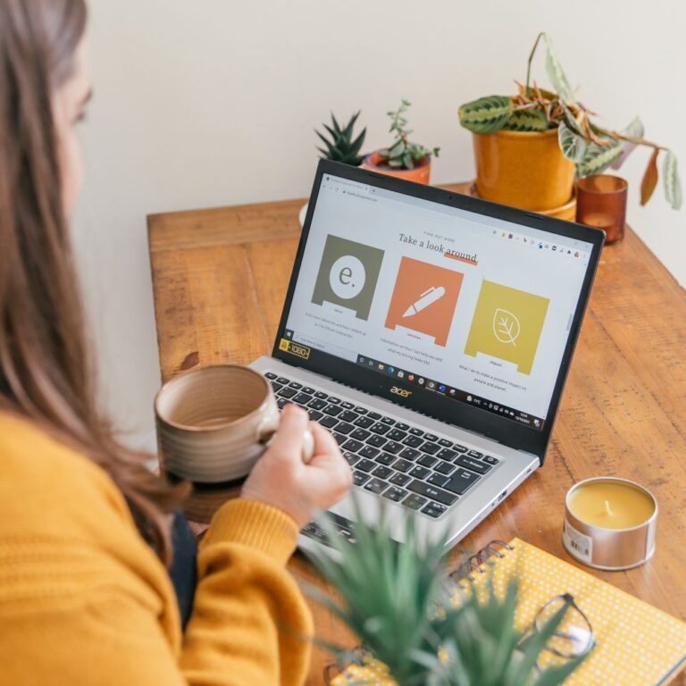 over the shoulder view of Rachel drinking coffee and looking at a laptop